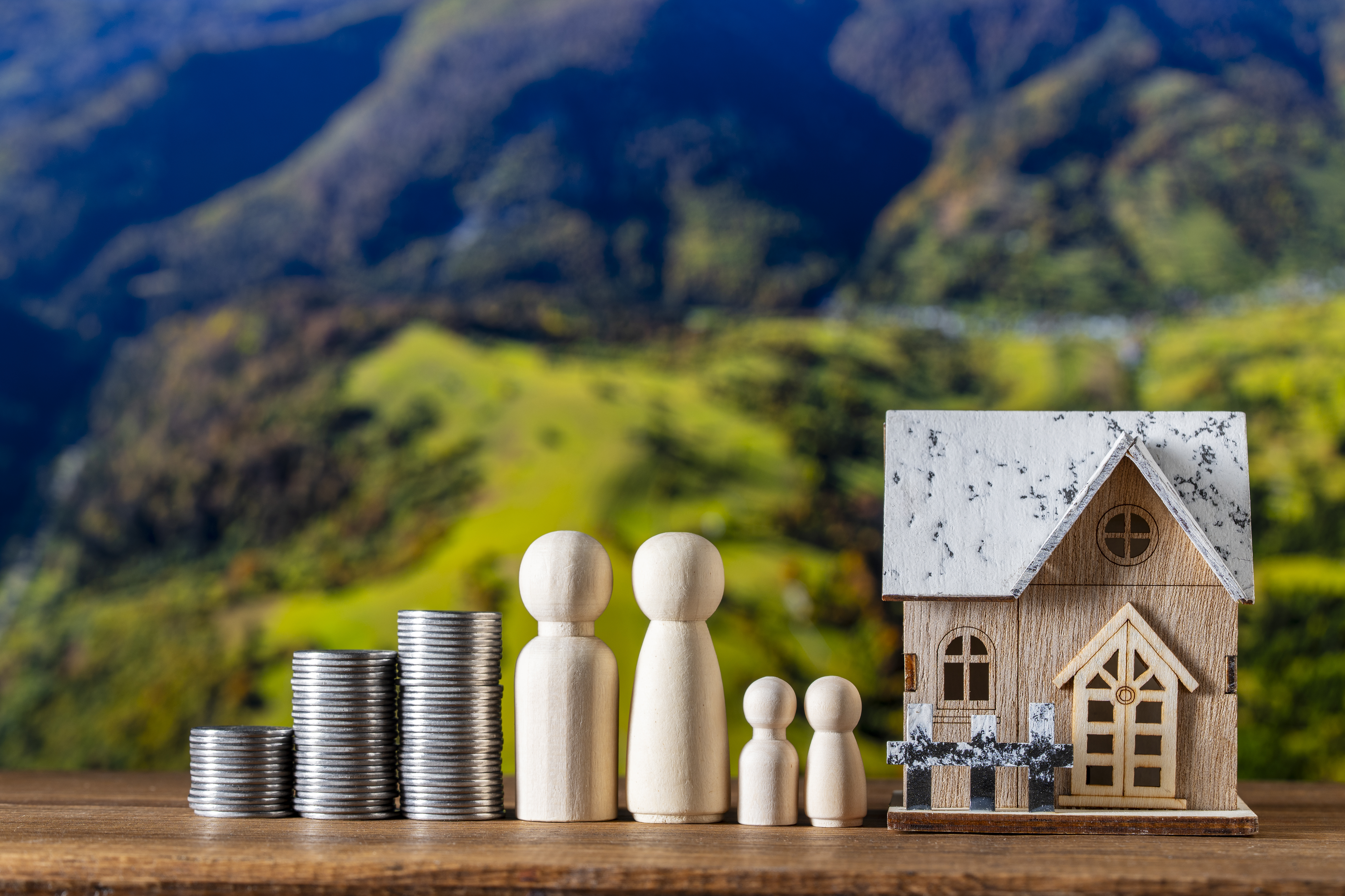 En modell av et lite hus sammen med en myntstabel og fire personfigurer.