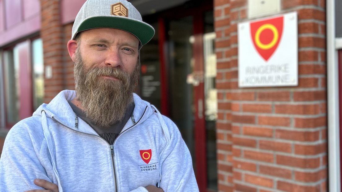 Mann med skjegg foran bygning med skilt til Ringerike kommune.