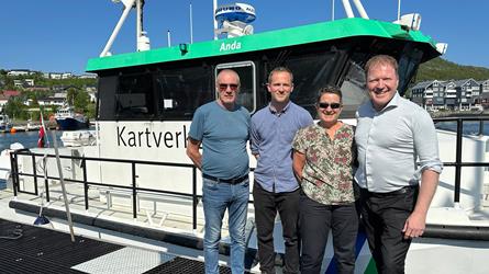 Karstein Vean, Pål Misje, Birte Noer Borrevik og Sigbjørn Gjelsvik står på kaia i Skjervøy. Sjømålingsfartøyet MB Anda er fortøyd i bakgrunnen.