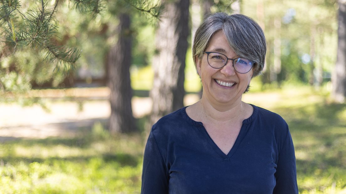 Kvinnelig ansatt i Kartverket fotografert utendørs i skogen