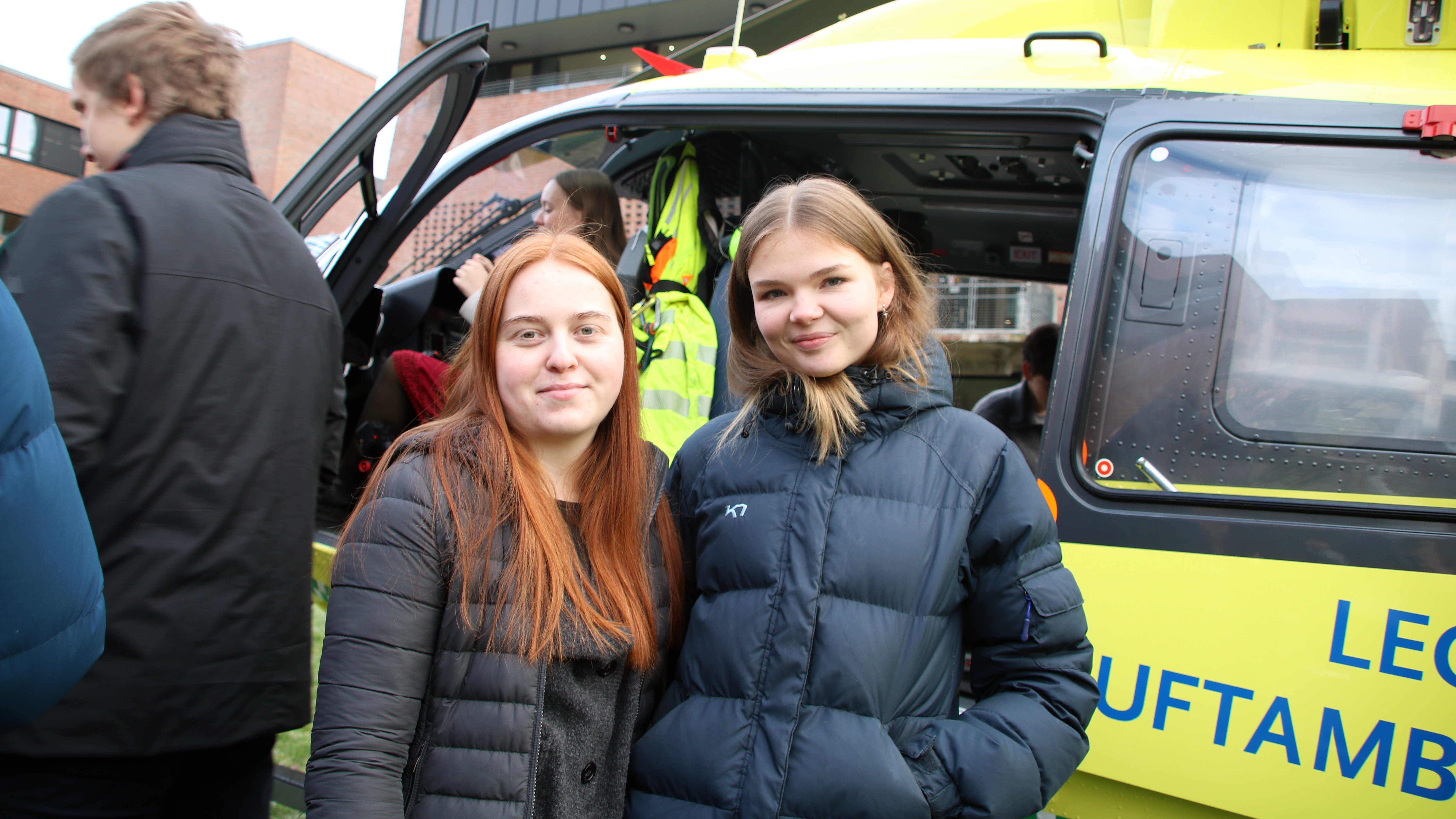 Ellen Runestad og Hanna Falang st&aring;r foran en luftambulanse.