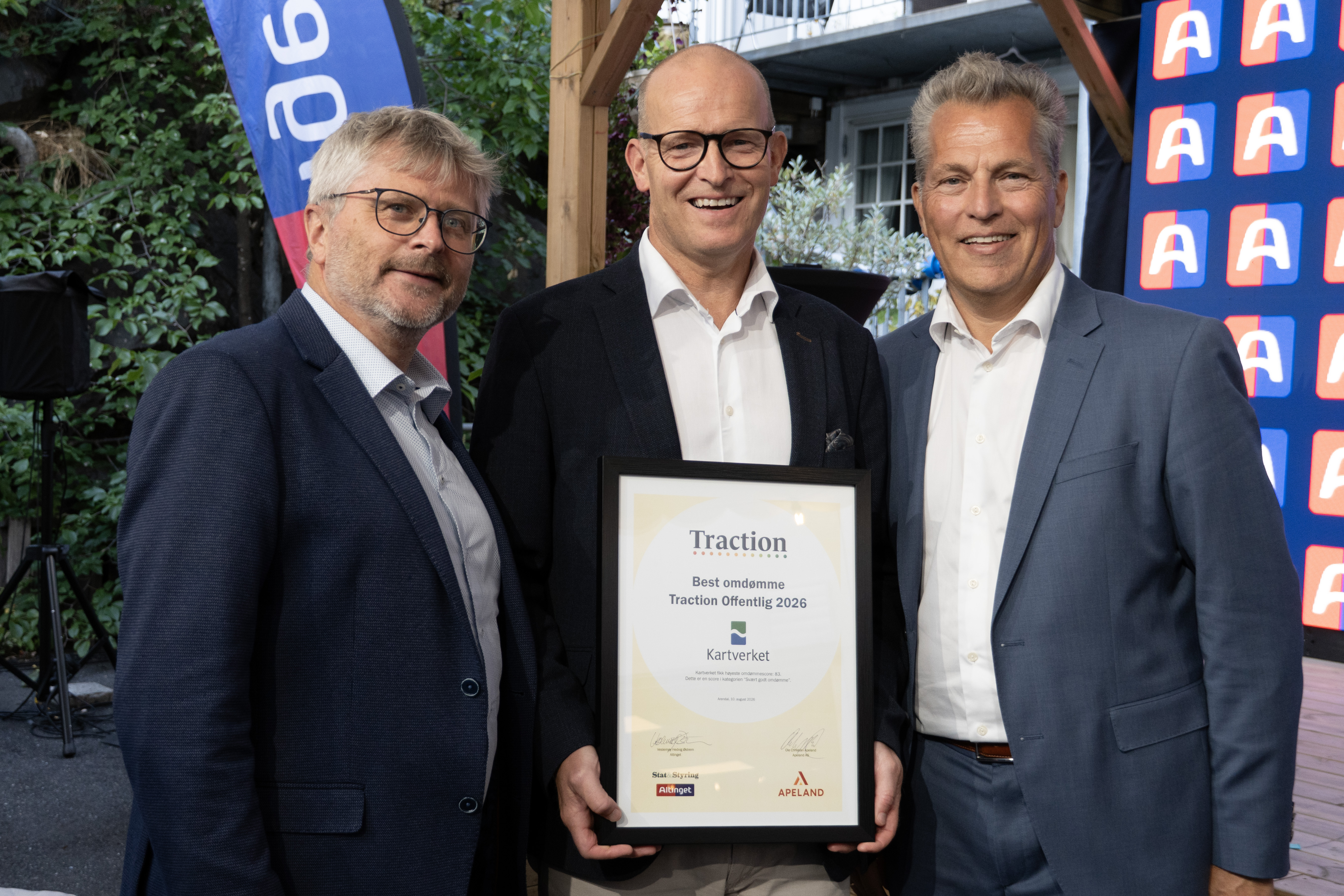 Tre personer i formelt antrekk står sammen og holder et innrammet diplom fra Traction Offentlig 2026. Diplomet viser at Kartverket er tildelt prisen for beste omdømme.
