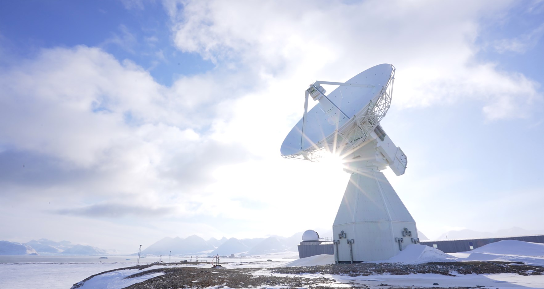 En stor satellittmottaker i et arktisk landskap i solskinn