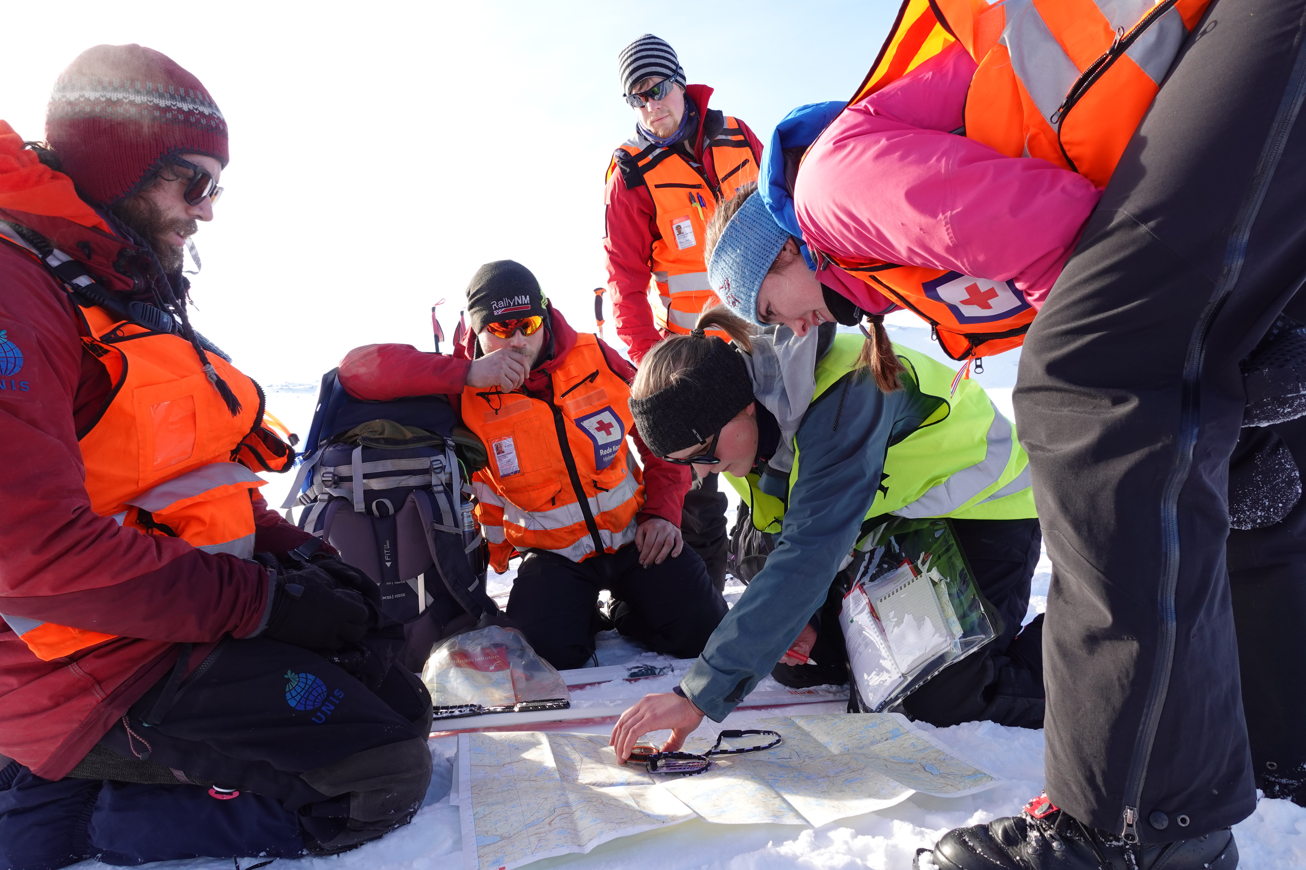 Fem menneske fr&aring; R&oslash;de Kors sjekkar kart og kompass i vinterver p&aring; Finse.