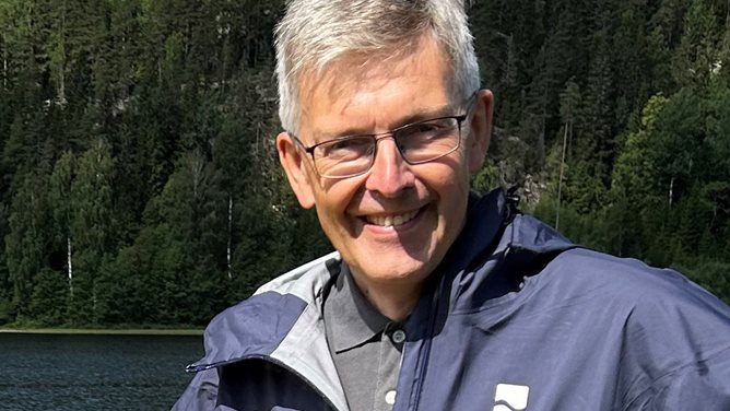 Anders Østeraas i Kartverket med tett granskog i bakgrunnen. Foto: Synne Storvik, Kartverket