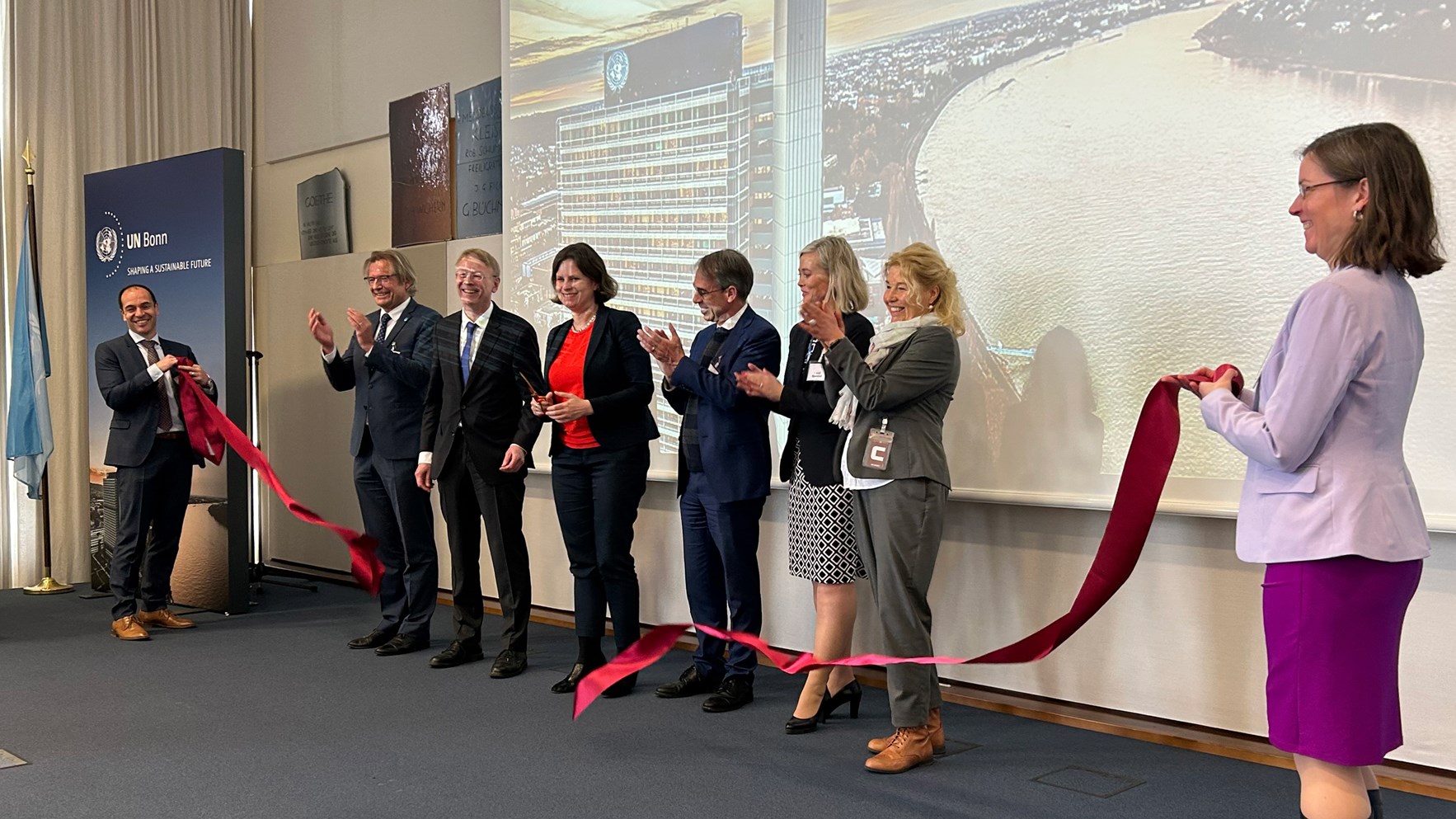 En gruppe p&aring; seks mennesker st&aring;r bak et r&oslash;dt silkeb&aring;nd som nettopp har blitt klippet over.