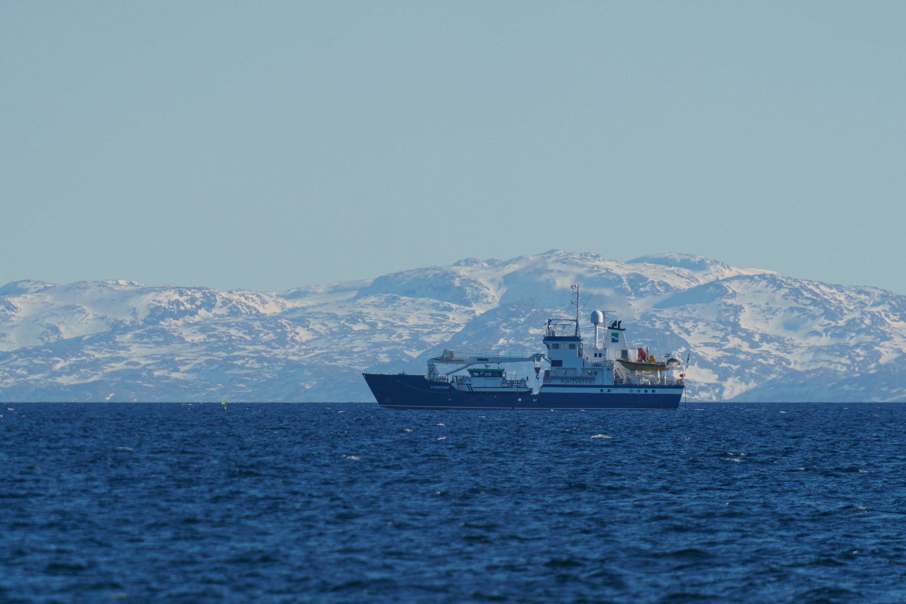Kartverkets måleskip Hydrograf i Varangerfjorden, med snødekte kystfjell i bakgrunnen.