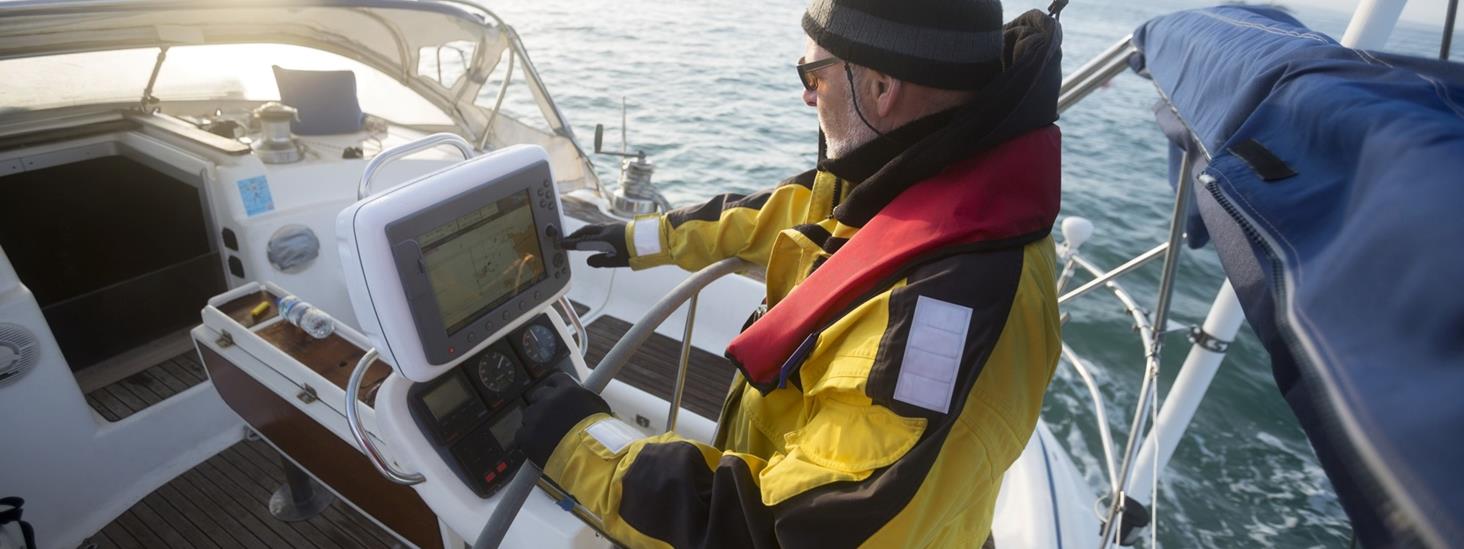 Mann i seilbåt peker på sjøkart i sin kartplotter. Foto: Adobestock