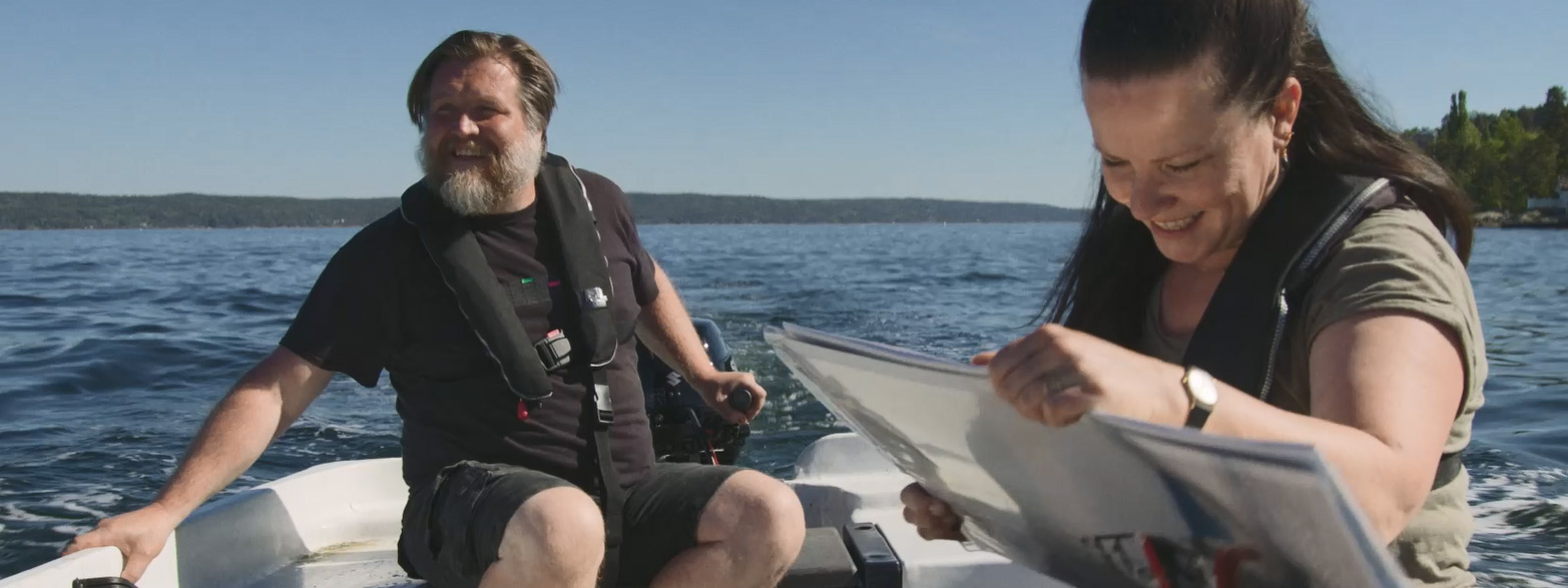 Mann styrer motorbåt mens dame sjekker sjøkartet. Foto: Kartverket