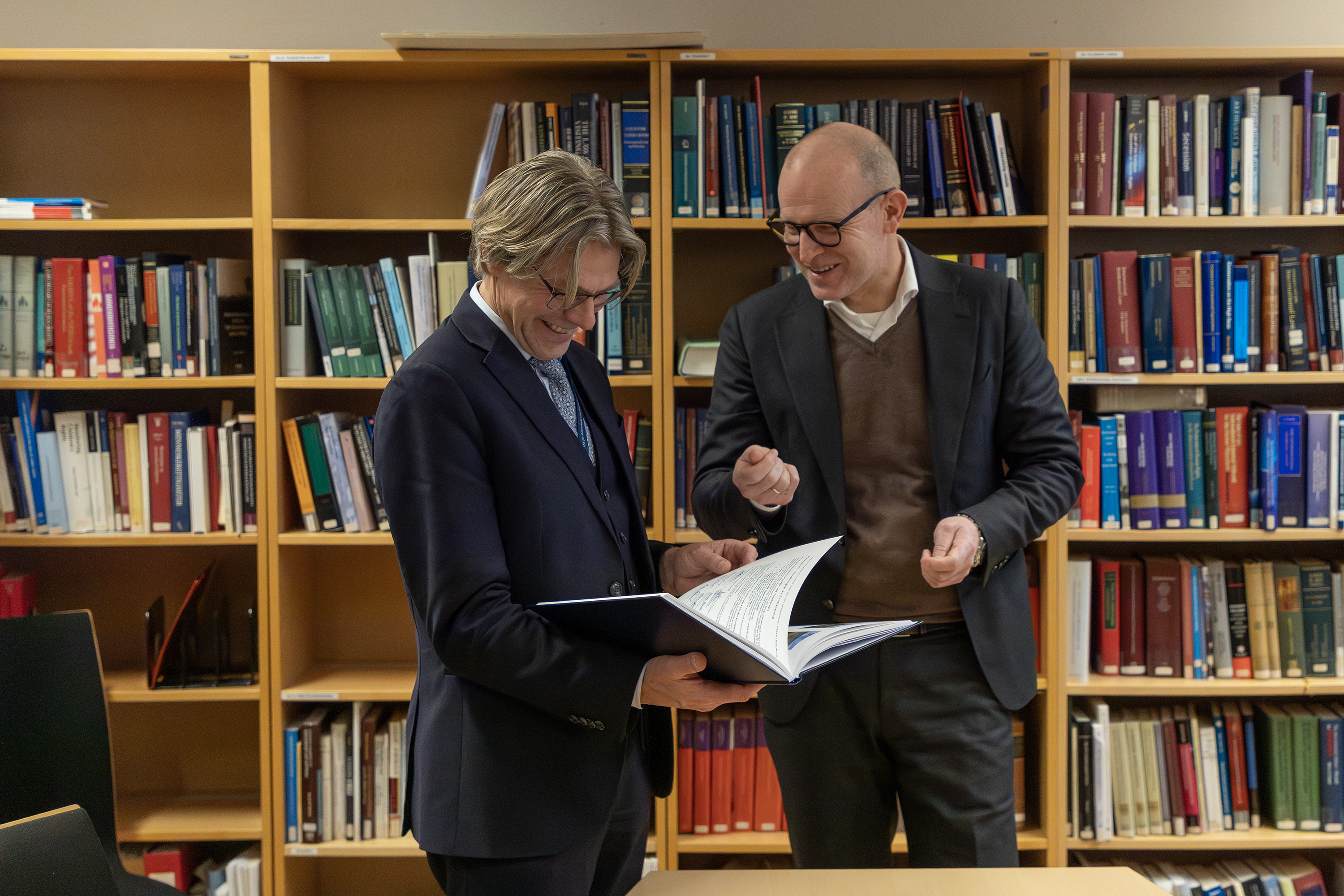 Gravemaskin og lastebiler i et åkerlandskap med hus i bakgrunnen.